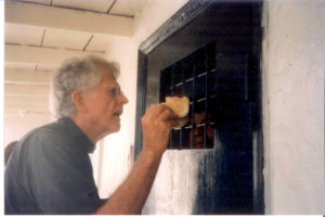 Fr Rick giving bread to prisoners in cell