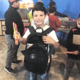A happy student with his new backpack and school supplies.
